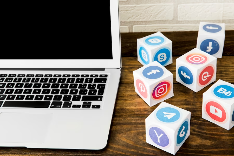 Laptop placed near a collection of social application icons on a table