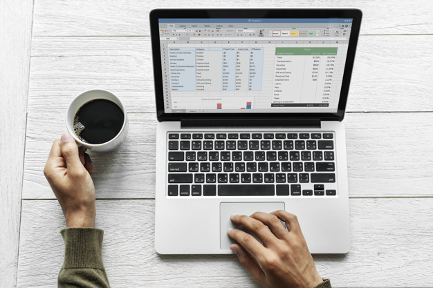 a man using laptop while holding a cup of coffee