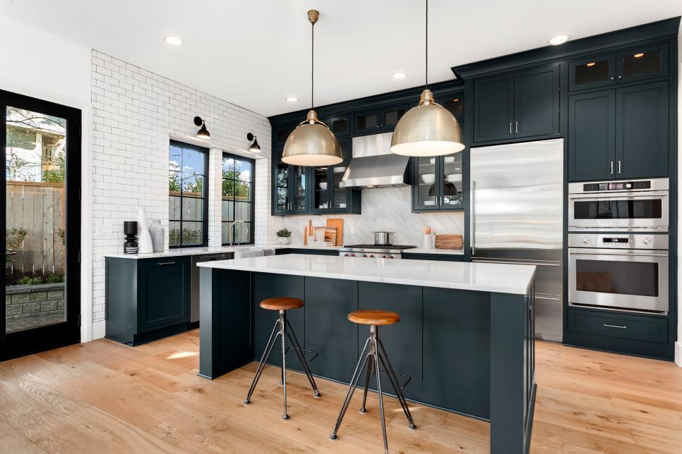 dark cabinets with woof stools. White subway tile going up the wall and black door frame. Stainless steel appliances. 