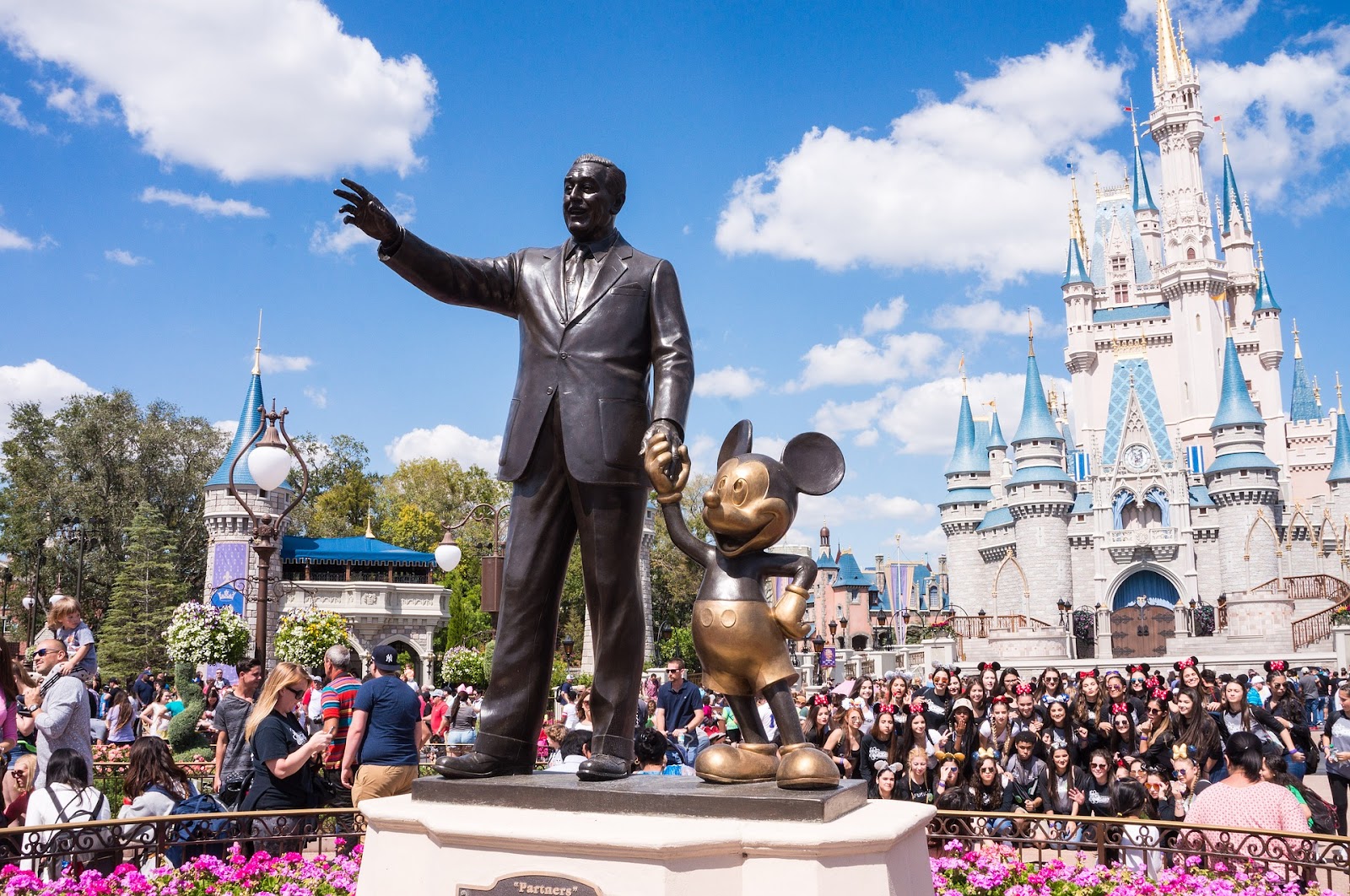 walt disney and mickey mouse partners black and gold statue in crowded walt disney world orlando theme park