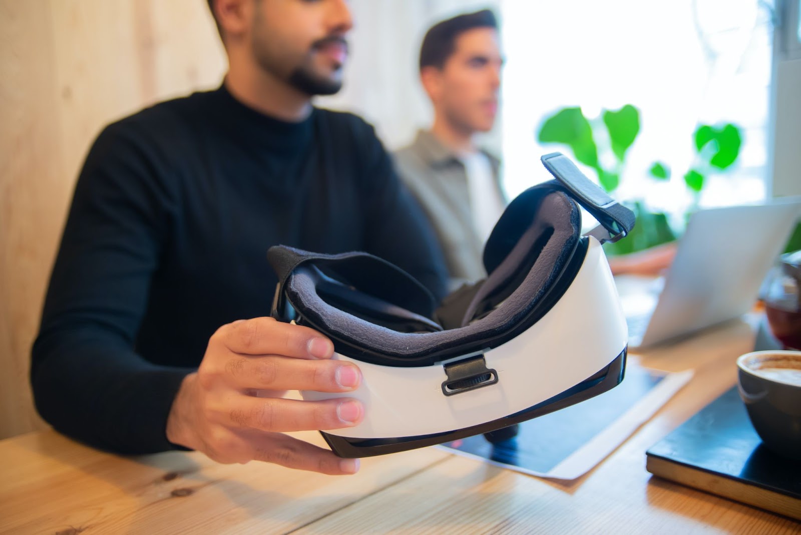 Man holding a VR headset at a desk