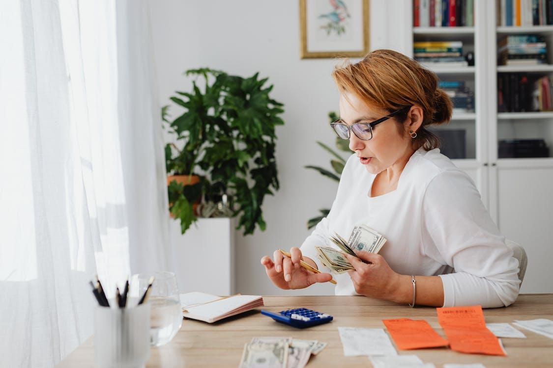 Free Woman Sitting at Desk Counting Money Stock Photo