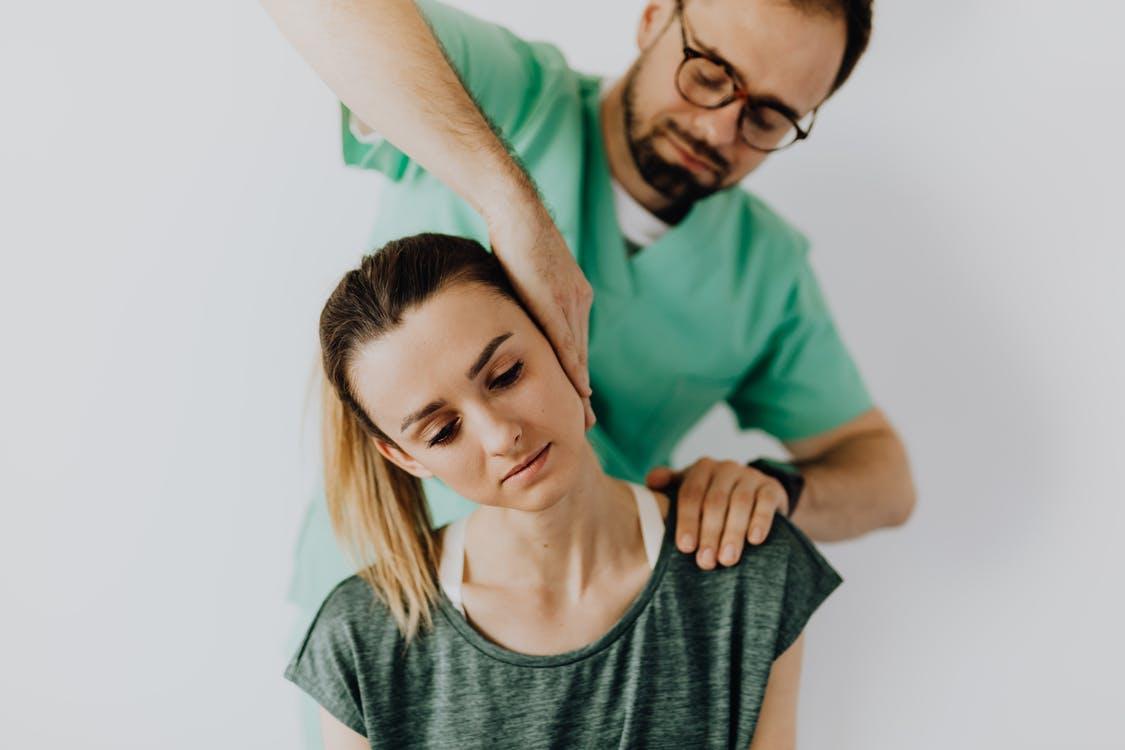 Focused massage therapist doing neck massage on woman