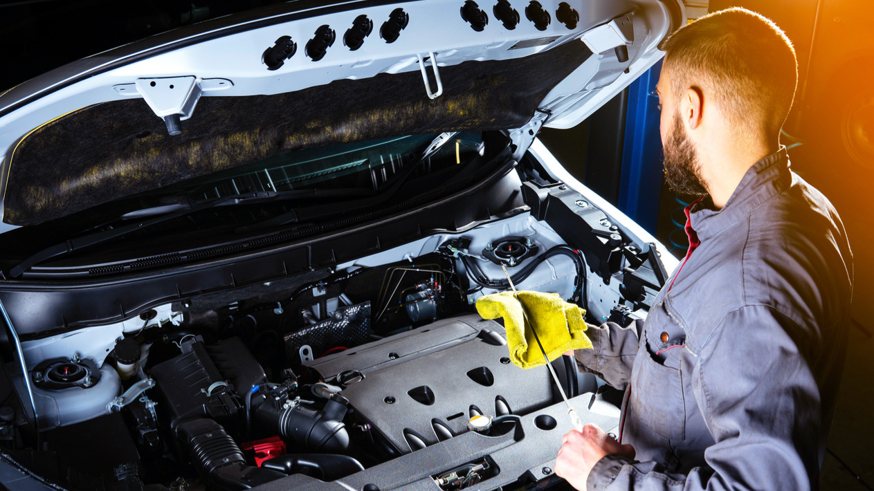 Image of a car mechanic checking oil.