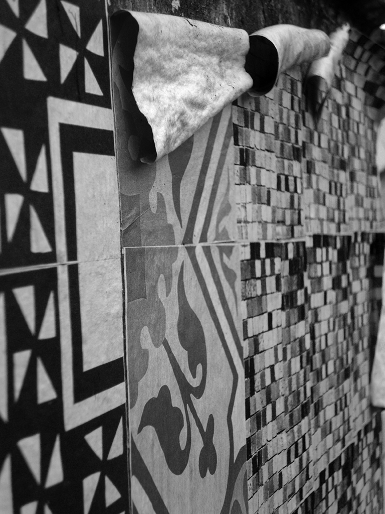 Detalhe dos Azulejos de Papel envelhecendo e descascando num muro de lote abandonado (Grupo Poro)