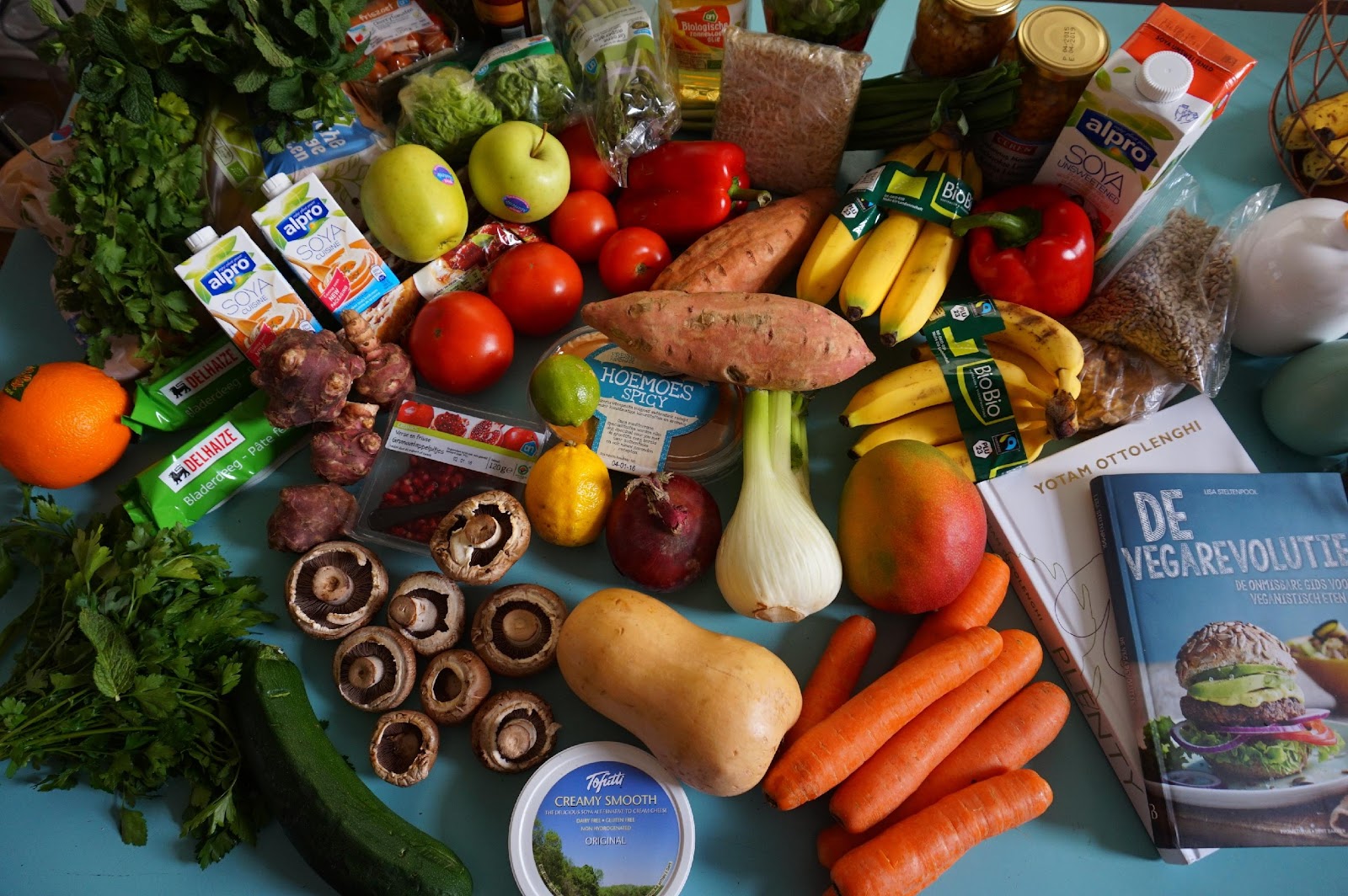 a table of carrots, apples, mushrooms, bananas, yams, plant-based milk, mango, bell peppers and apples