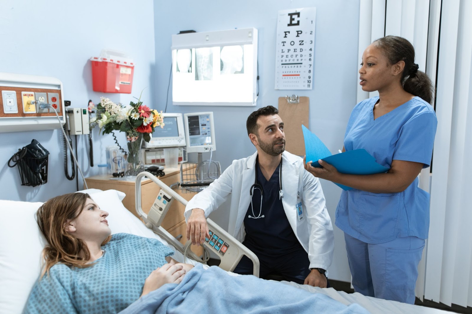 Doctor looking at nurse while she explains the patient's chart to the patient