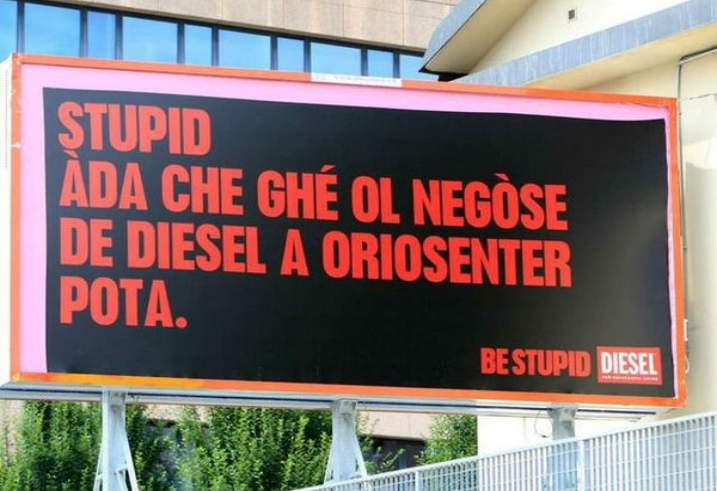 manifesto pubblicitario della campagna Be stupid by Diesel con scritto in rosso su sfondo nero "Stupid ada che ghè ol negose de diesel a oriosenter pota" in dialetto bergamasco 