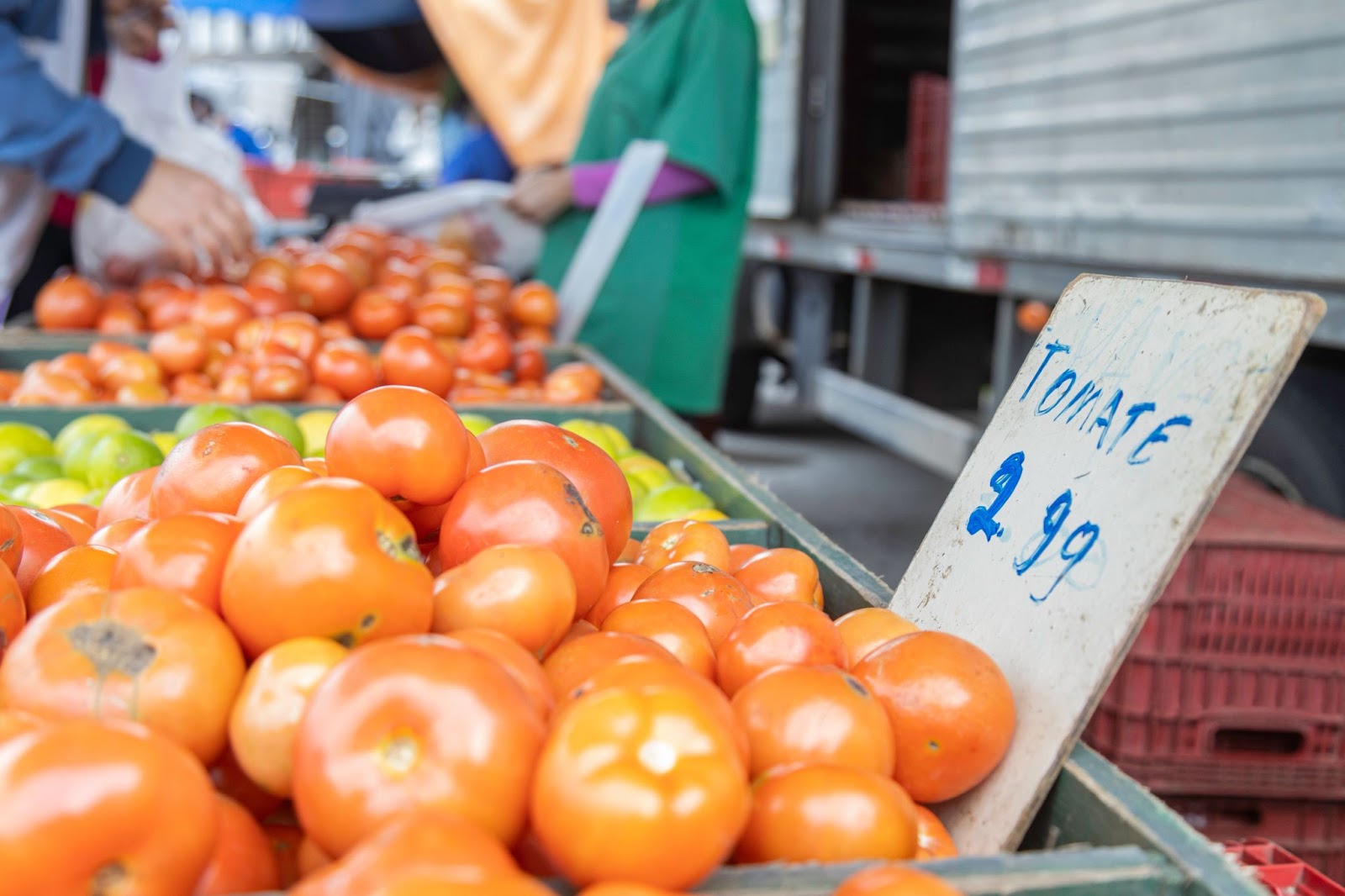 Frutas e legumes expostos para venda em um mercado público. Há principalmente tomates e limões.