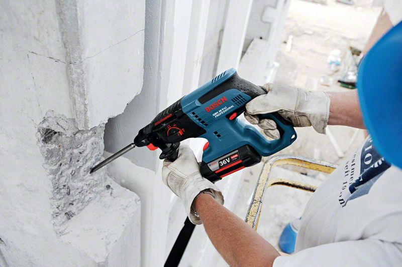 Profissional da construção civil usando martelete bosch para perfurar parede de concreto.