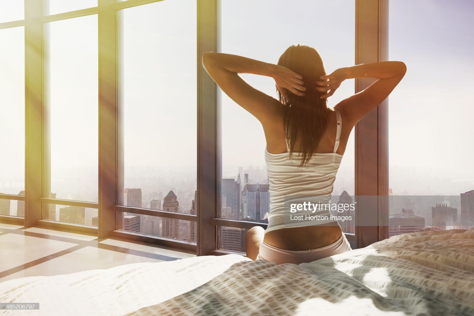 D:\Documenti\posts\posts\Miami\foto\donne normali\young-woman-sitting-on-bed-stretching-overlooking-city-picture-id485206797.jpg