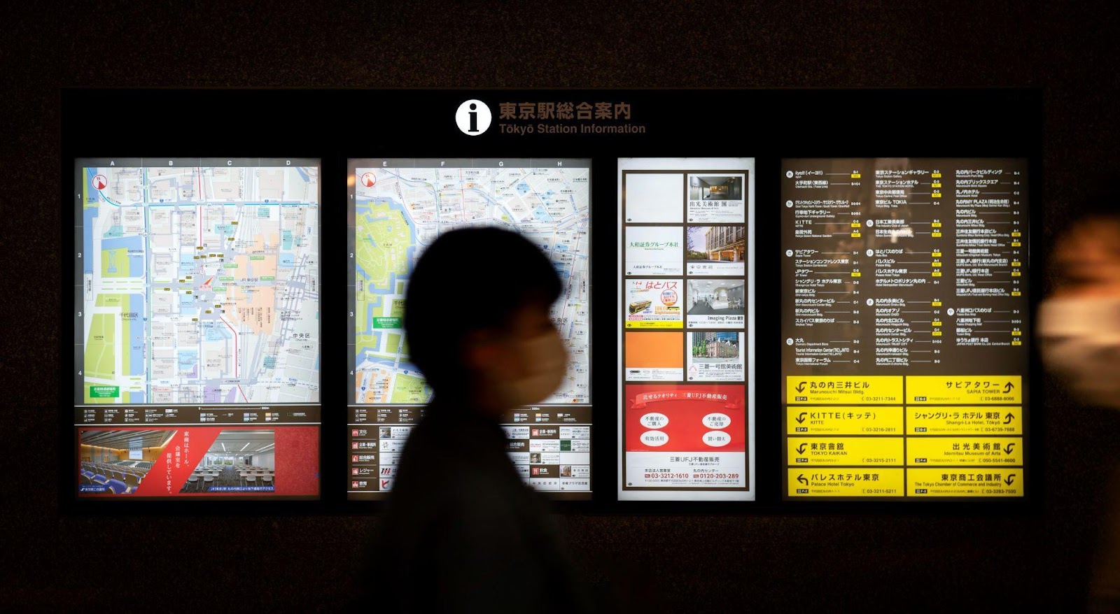 A man passing in front of a digital signage in a subway station. 
