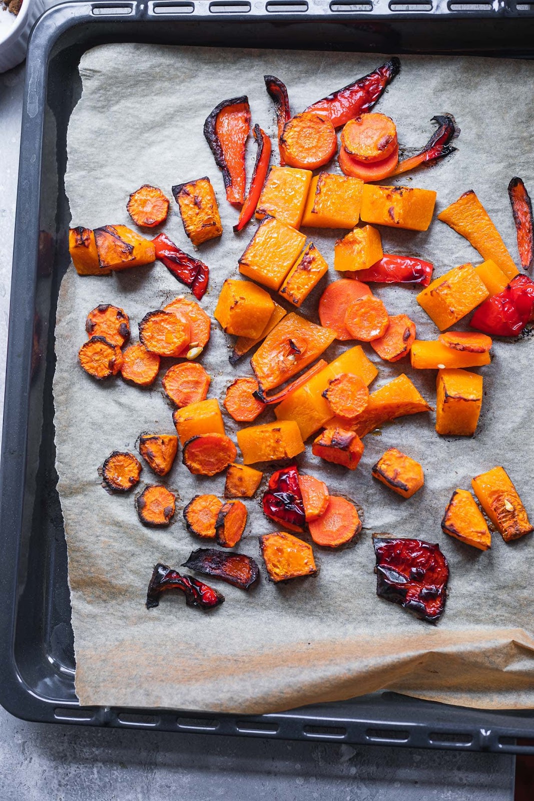 Roasted butternut squash, carrots and bell pepper on a baking tray