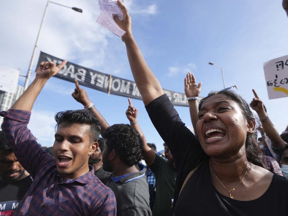 Sri Lankan protestors shout chants and raise their hands as they demand the President resign