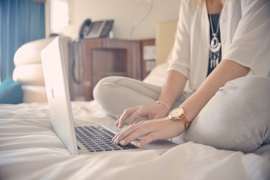 blogger sat on a bed working from their laptop