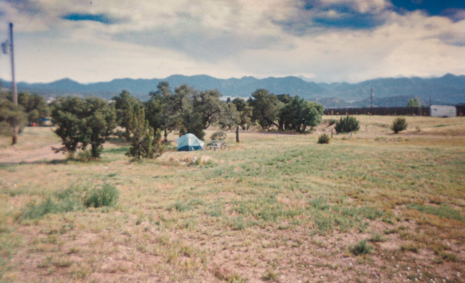 Blue domed tent with bicycle nearby and distant mountains on the horizon. 