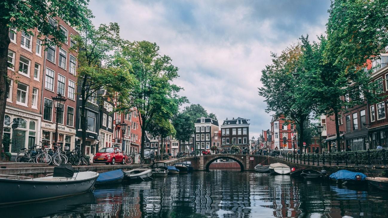 Tradicional canal de Ámsterdam con barcas a cada lado del puente 