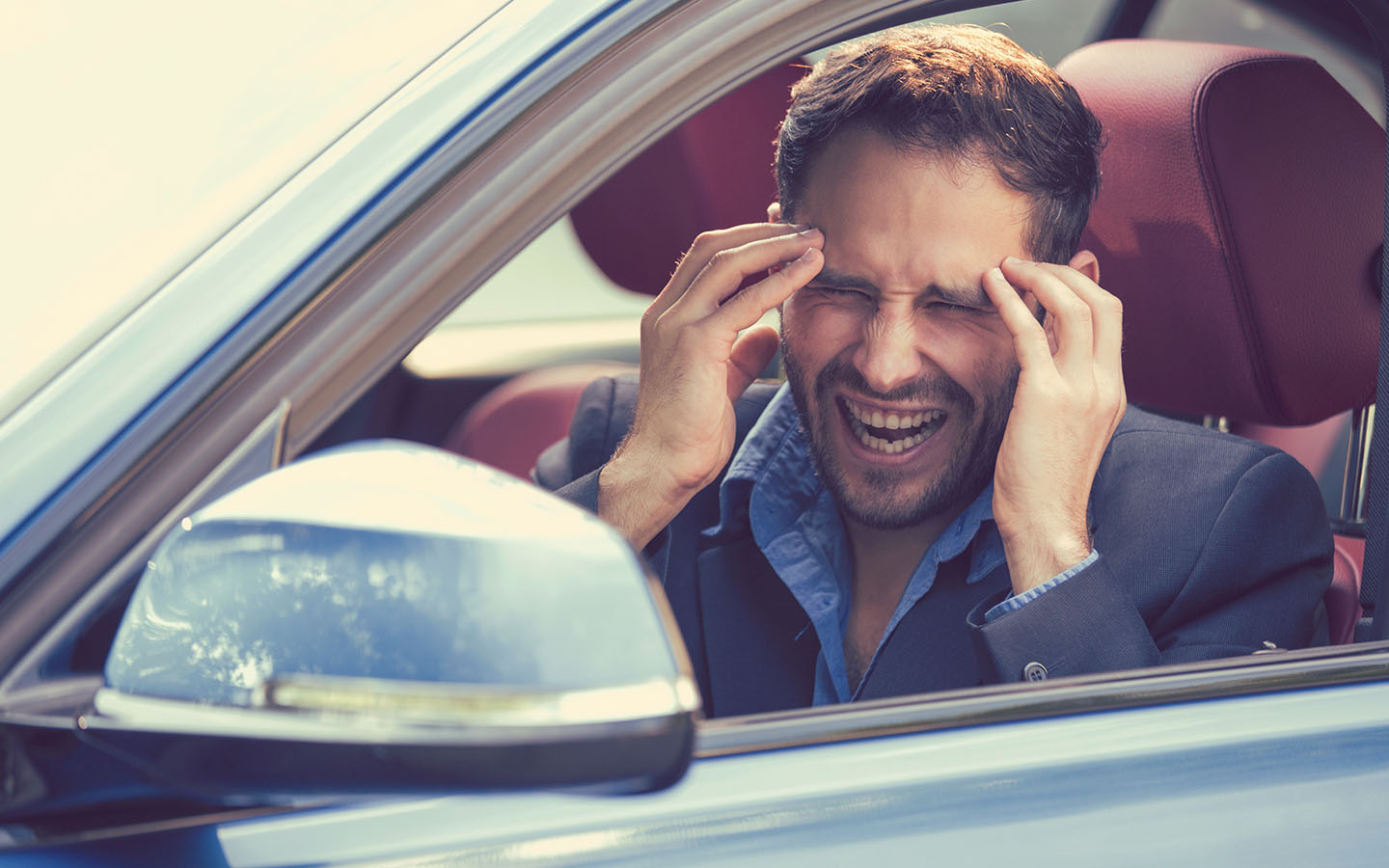 man stressed out in car because of loud engine noises which are among the engine valve problem symptoms