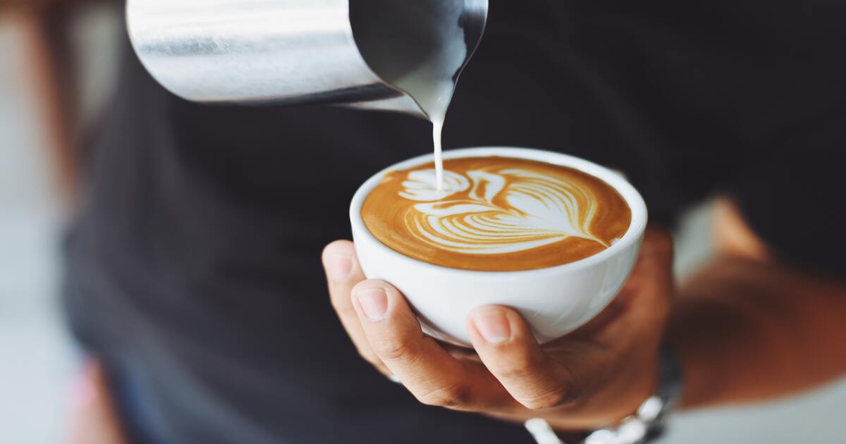 Small business holiday gift guide–An image of a person pouring milk into a cappuccino creating foam art.