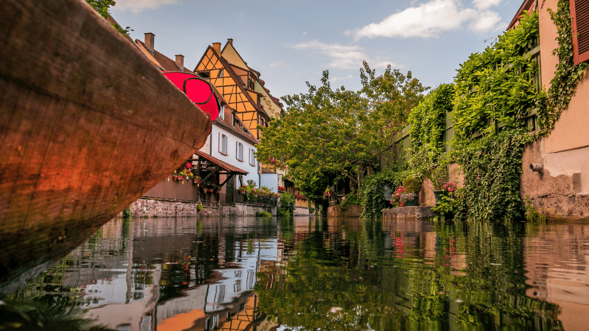 A boat floats in the water with old buildings in the background