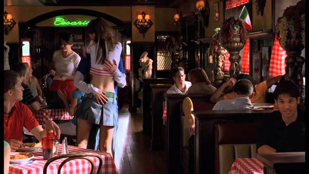 A scene in a diner: a girl in a short skirt and crop top throws her arms around Viola-as-Sebastian, who responds by putting his hands around her waist.