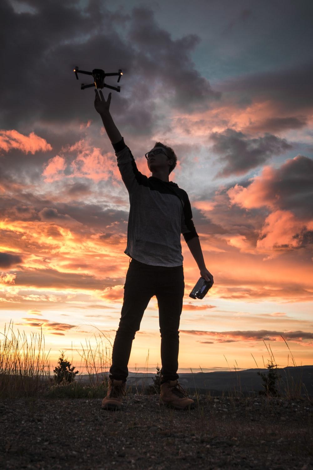 silhouette photo of man holding up drone