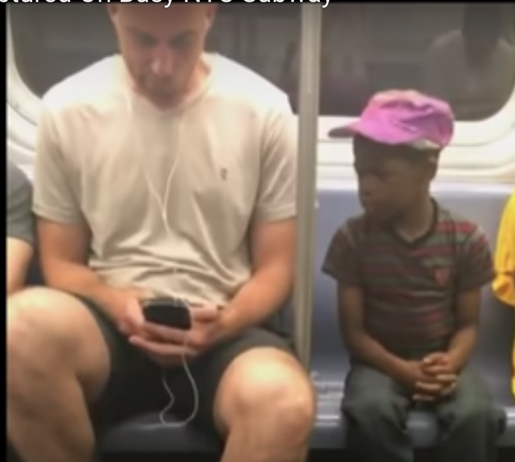 Boy staring at mans phone on subway