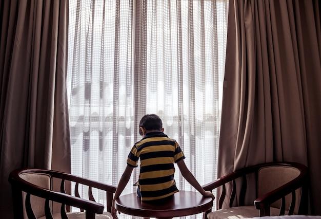 Free photo boy sitting on a table looking down down