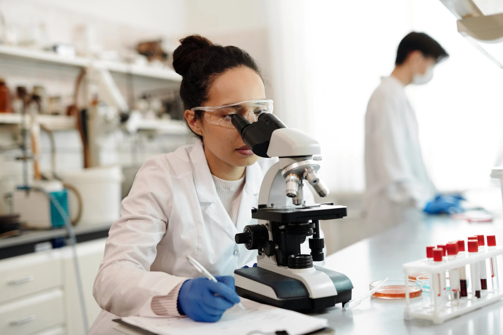 Une femme au microscope qui a choisi la méthode de recherche pour son domaine de travail.