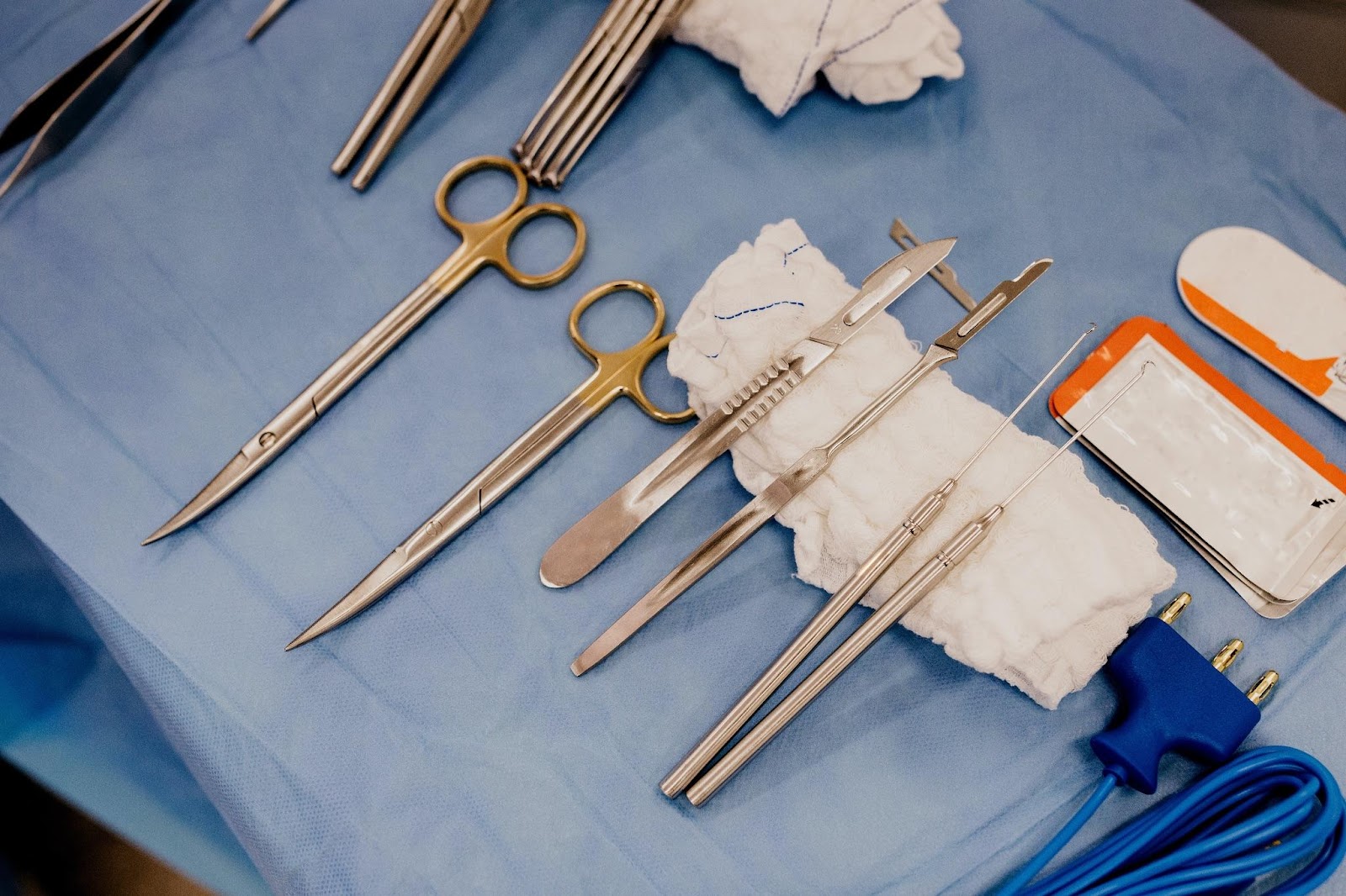 Chirurgické nástroje položené na modrém podkladu.