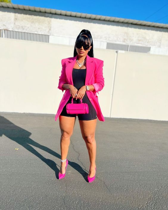 A lady wearing black shorts with a pink blazer and pink shoes for women