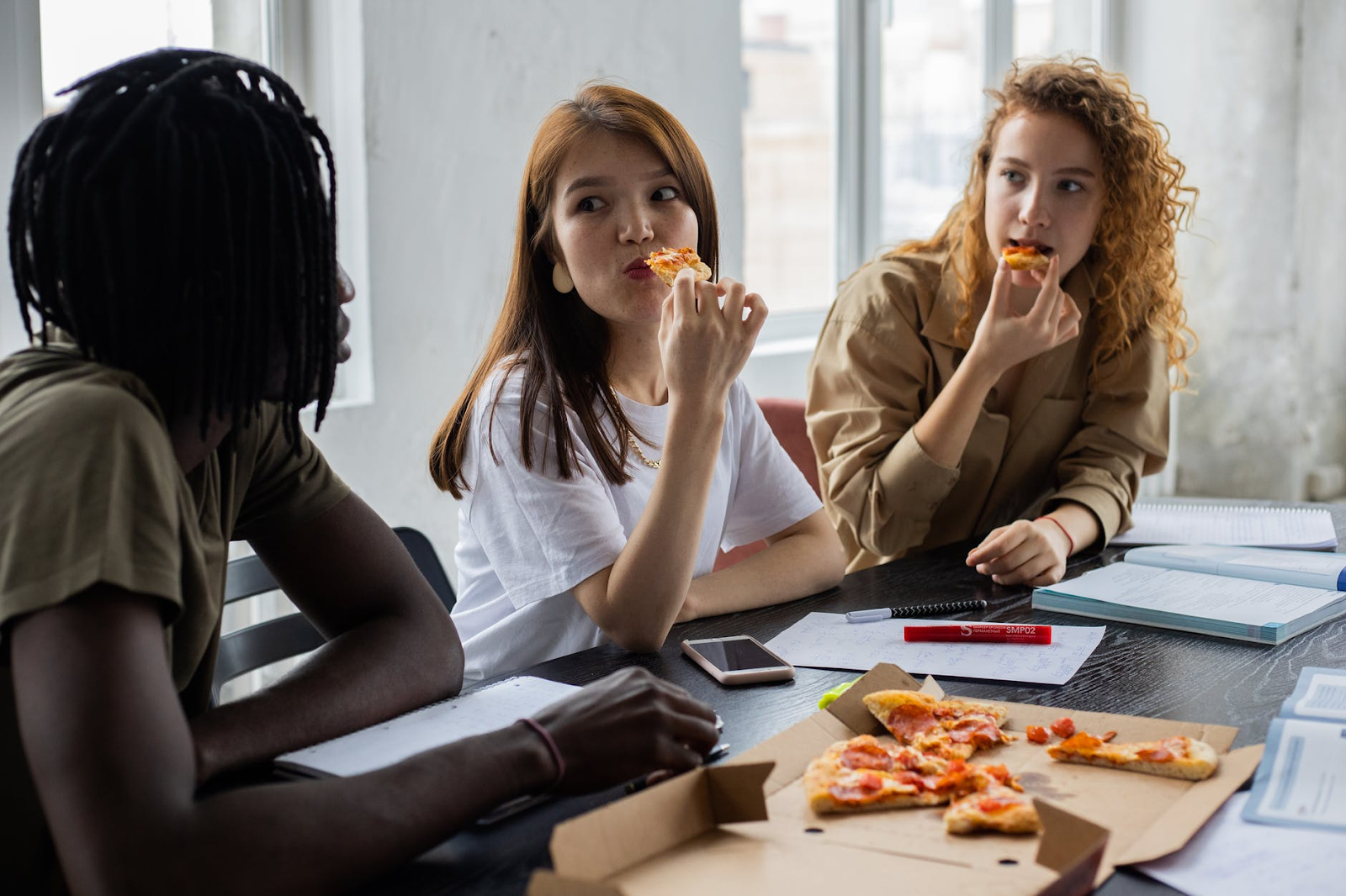 Three women eating pizza and talking