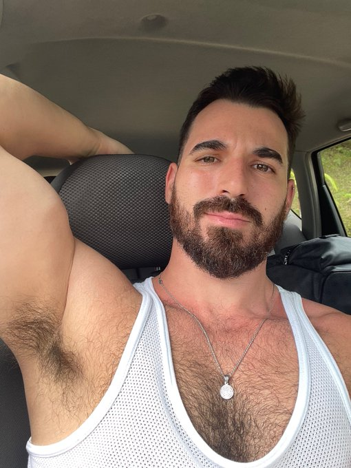 Thick Macho posing in a car selfie wearing a white mesh tanktop revealing his gay hairy chest