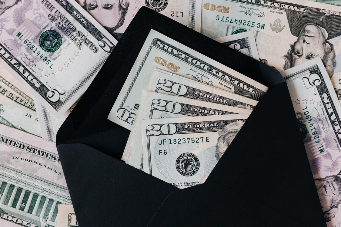Free From above of dollar bills in opened black envelope placed on stack of United states cash money as concept of personal income Stock Photo