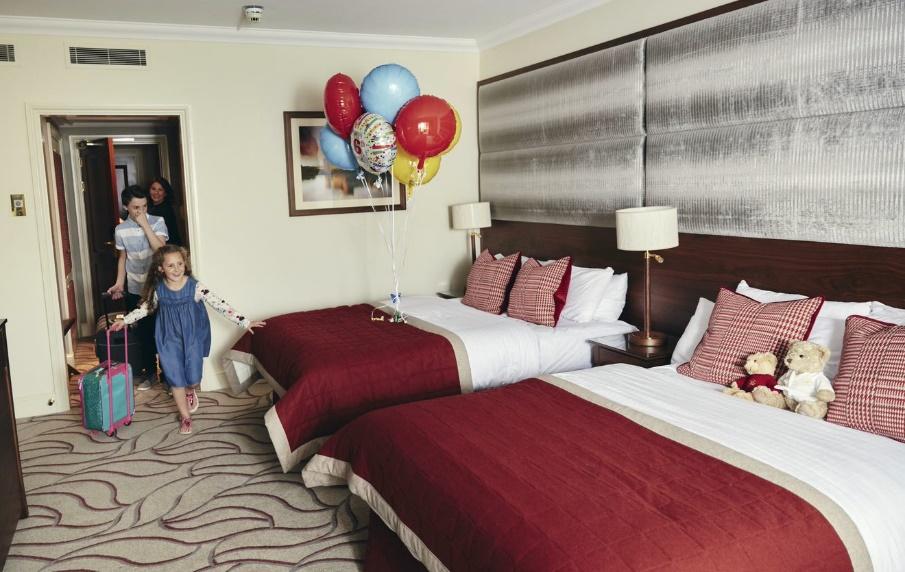A child walking in a hotel room with two beds

Description automatically generated
