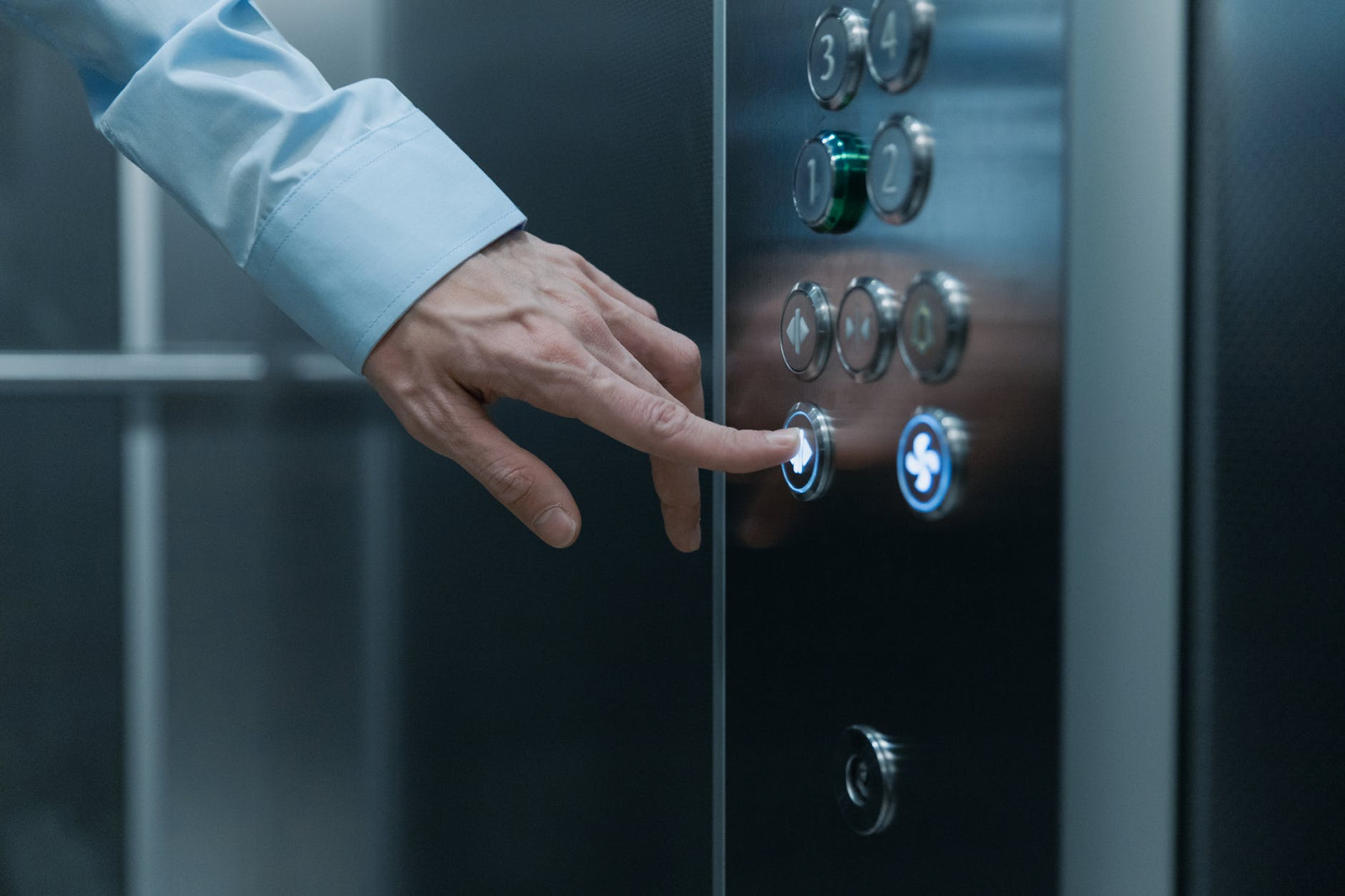 Elevator pitch: homem de negócios apertando um botão de andar dentro do elevador.