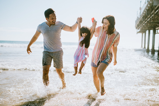 a husband and wife holding their daughter's hand while in the beach feeling happy and connected. if you are struggling with your couple's relationship and feeling alone in your marriage, relationship counseling can help to bring you two closer and stronger. Call today for marriage counseling in Woodland Hills, CA 91364