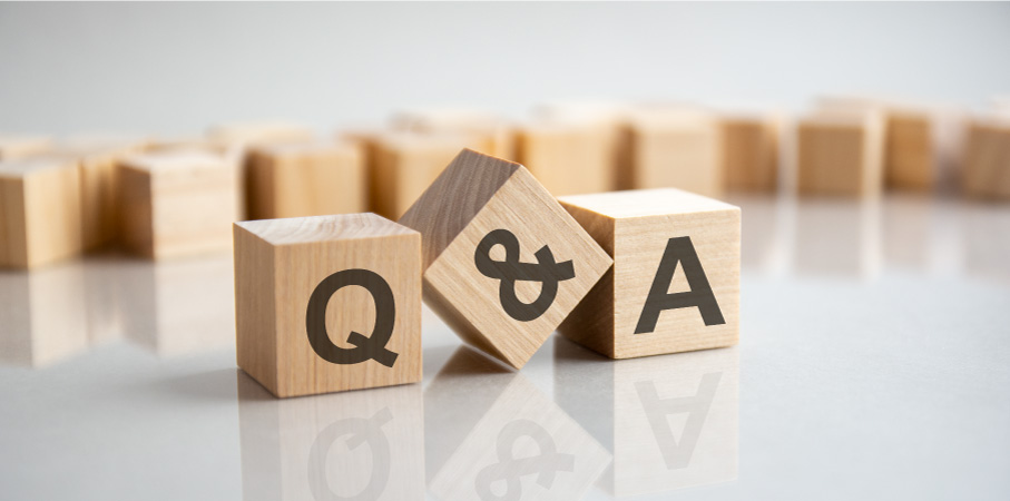 Wooden blocks labeled “Q & A" are sitting on a shiny white table with more unmarked wooden blocks in the background.