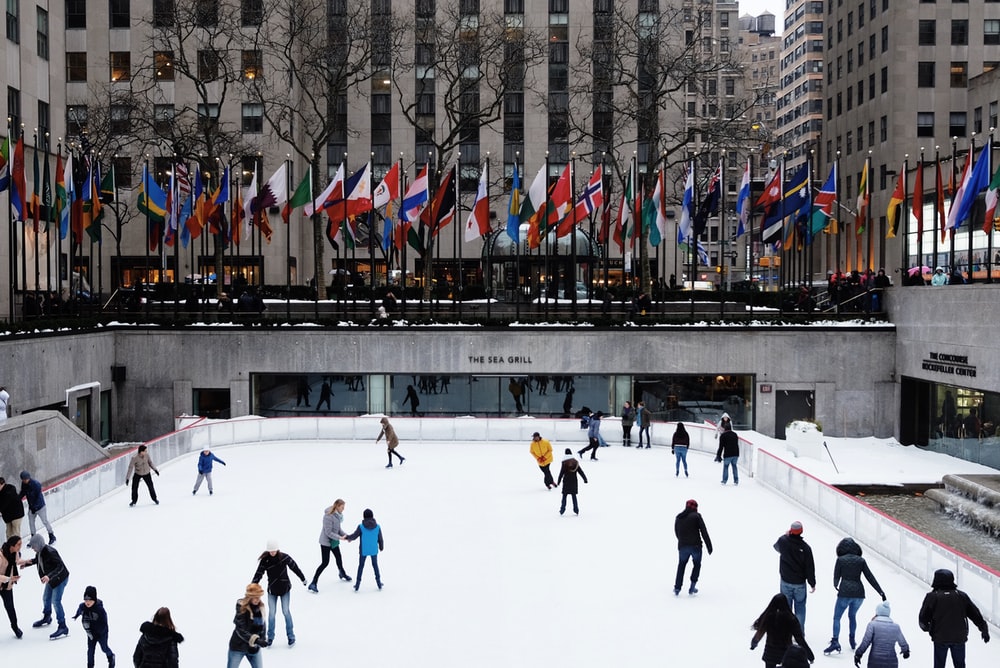 people ice skating on field surrounded by high-rise buildings