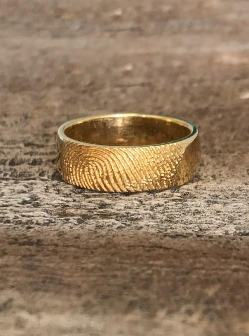 A gold ring on a stone surface

Description automatically generated with low confidence