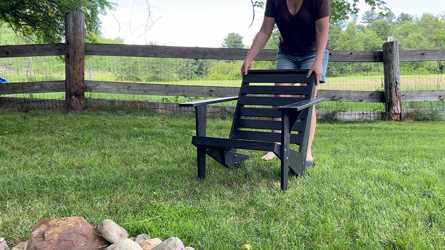 Woman placing Adirondack chair on the grass