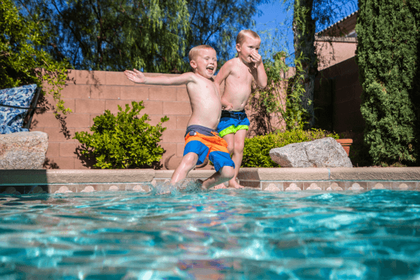 Two boys jumping into swimming pool