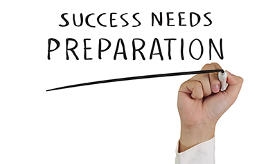 A hand holding a white pen with the words, "Success Needs Preparation"