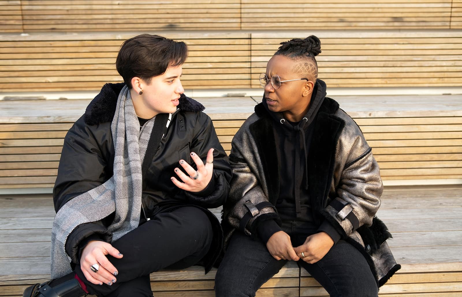 Two persons sitting on a bench, facing each other.