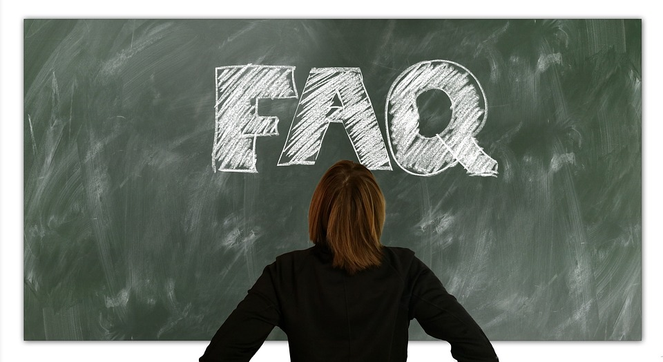 A woman looking at a chalkboard with FAQ written on it.