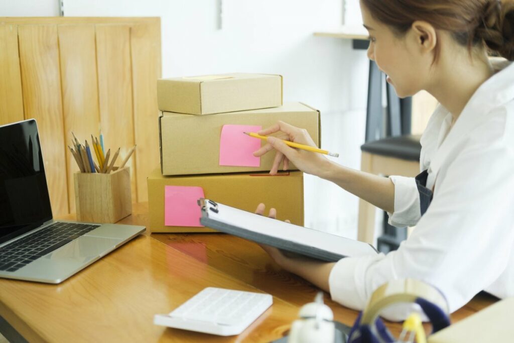 Person counts and labels boxes with sticky notes while holding a clipboard