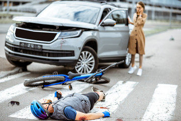 Accident with injured cyclist lying on the pedestrian crossing near the broken bicycle.