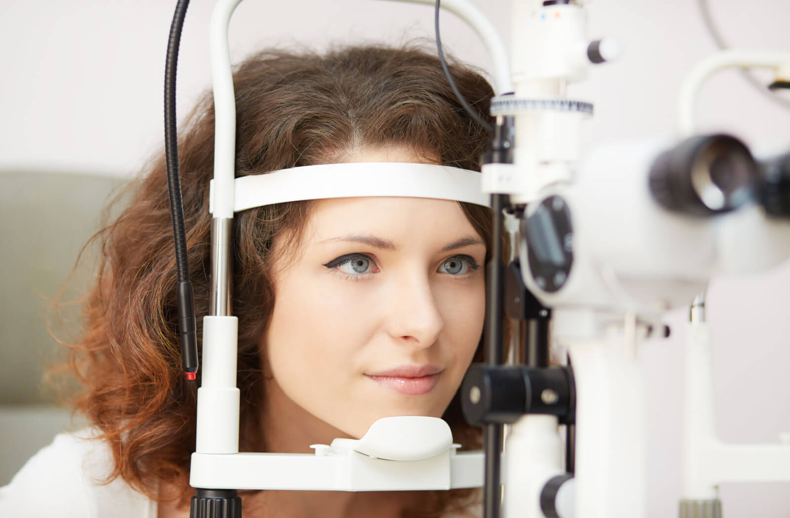 A woman in an optometrist's office looking into a machine that tests her vision.