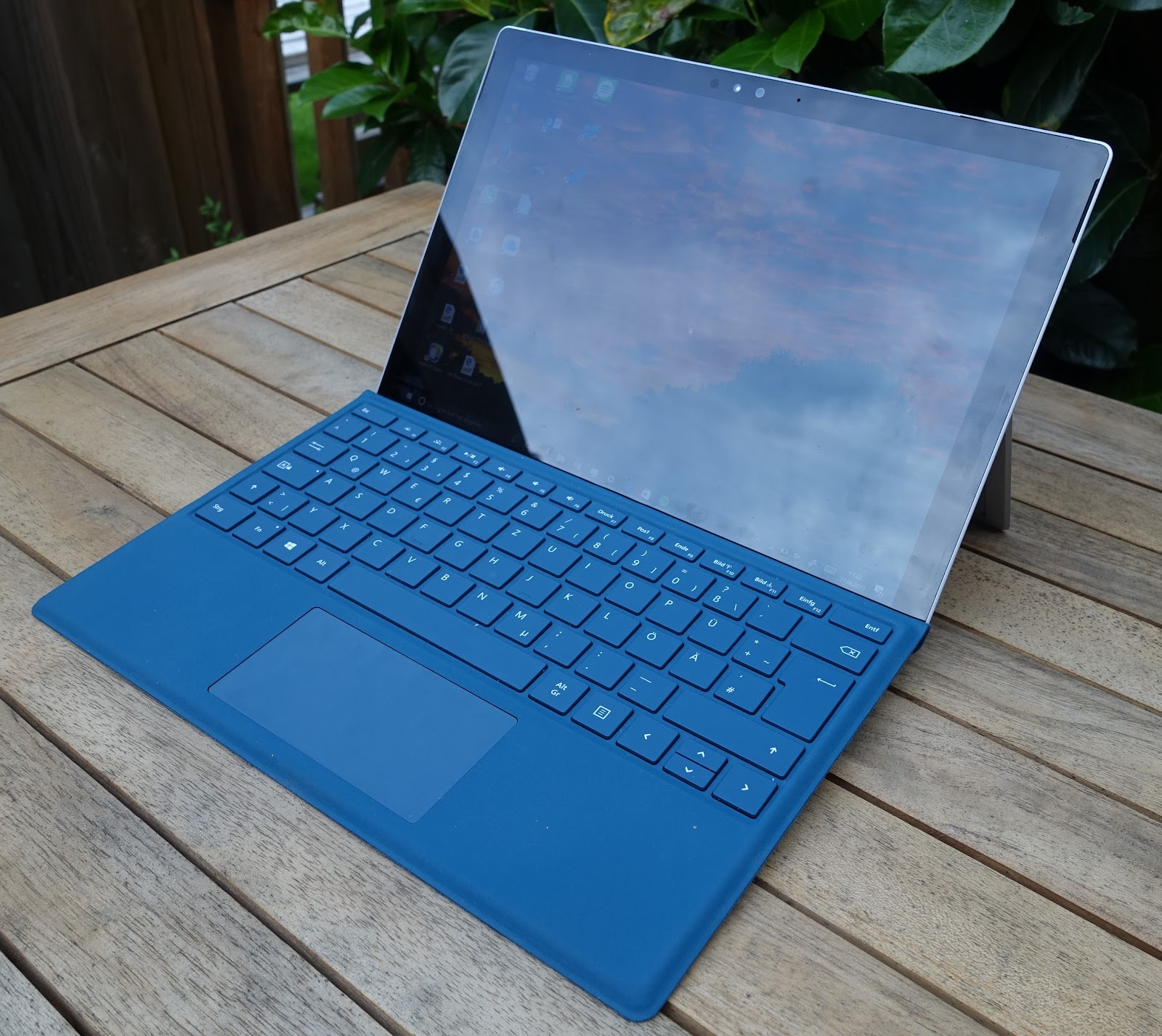 Microsoft Surface Pro 7+ laptop in the blue color is in the wooden desk with open display.