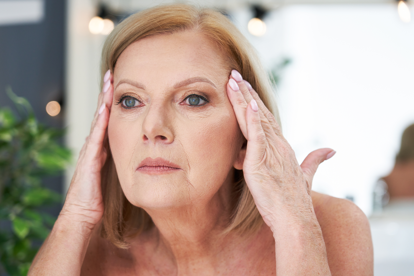 Woman looking at wrinkles in the mirror and thinking about botox